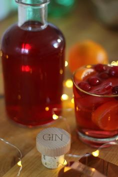 a bottle of gin sitting next to a glass filled with red wine and oranges