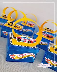 hot wheels birthday party favors in blue plastic containers with yellow ribbon and gold foil rings