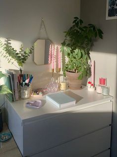 a white desk topped with lots of office supplies and a potted plant next to it