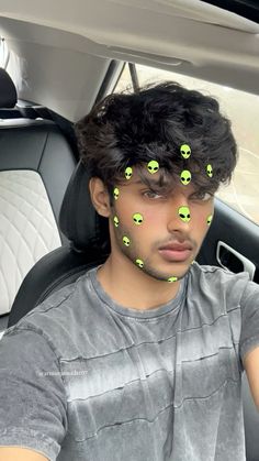 a man sitting in the back seat of a car with green alien faces on his forehead