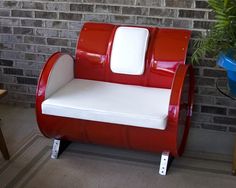 a red and white chair sitting in front of a brick wall next to a potted plant