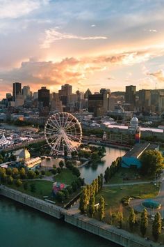 an aerial view of a city with a ferris wheel in the foreground and a river running through it