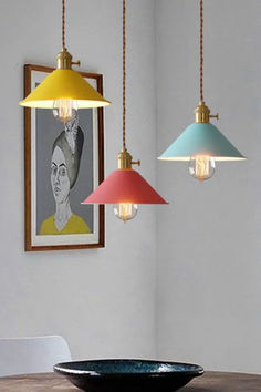 three pendant lights hanging from the ceiling above a dining room table with a bowl on it