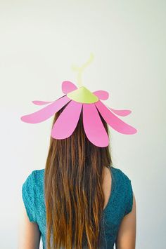 a woman with long hair wearing a pink flower shaped paper hat on top of her head