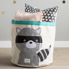 a raccoon storage bag sitting on top of a wooden floor next to pillows