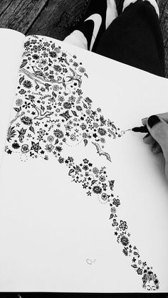 a person is drawing with black ink on white paper