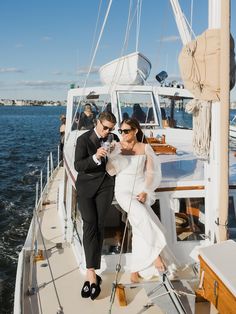 a bride and groom on the deck of a sailboat drinking water from a bottle