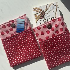 two red bags with hearts on them and a book in the middle one has a blue clip