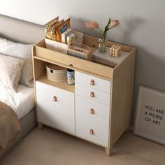 a white dresser sitting next to a bed with flowers on top of it in a bedroom