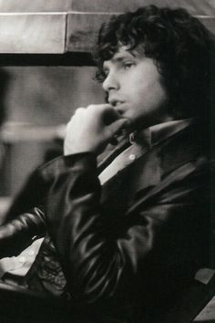 a black and white photo of a man in a leather jacket talking on a cell phone