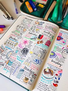 an open notebook with lots of doodles and markers on it next to some pens