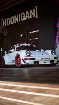 a white sports car parked in front of a building with the word hoonigani on it