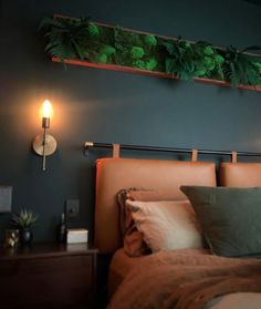 a bed that has some plants on the headboard and lights in the wall above it