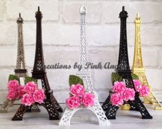 the miniature eiffel tower has pink flowers in it's centerpieces