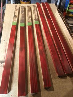 several pieces of red wood sitting on top of a wooden table next to a pair of scissors