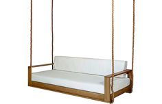 a wooden swing bed with white sheets on it's back and seat cushiones