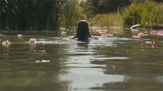 a woman is swimming in the water with pink flowers