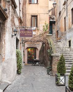 an alleyway with steps leading up to a restaurant in the middle of it and potted plants on either side