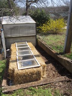 an outdoor area with hay in the ground and a small shed on the other side