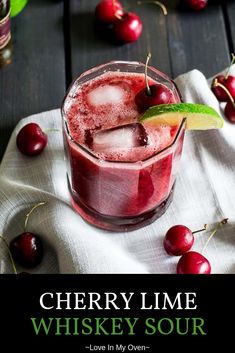 a glass filled with ice and cherries sitting on top of a table next to a napkin