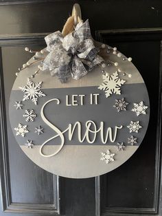 a sign that says let it snow hanging on a door with a bow and ribbon