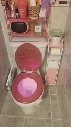 a pink toilet in a bathroom next to a shelf