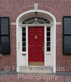 a red door with black shutters on a brick building