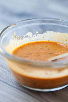 a glass bowl filled with sauce on top of a wooden table