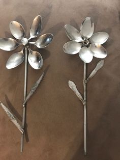 three metal spoons with flowers on them sitting on top of a brown tablecloth