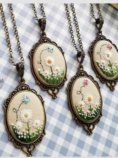 three necklaces with daisies and daisies in them on a checkered tablecloth