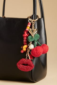 a black purse with some charms attached to it's handle and two red lips