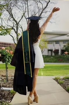 a woman is walking down the sidewalk with her graduation cap and gown over her shoulder