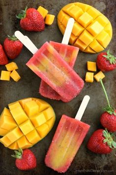 popsicles with mangos and strawberries are arranged on a baking sheet, ready to be eaten