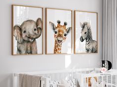 three pictures of animals hanging on the wall in a baby's room with a crib