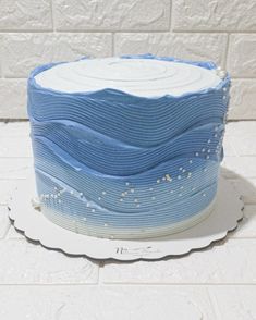 a blue cake with white frosting and sprinkles on the top is sitting on a plate