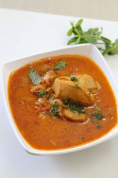 a white bowl filled with soup and garnished with parsley on the side