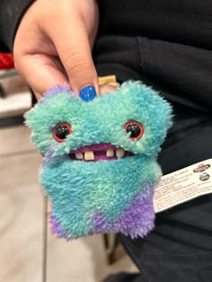 a person is holding a blue and purple stuffed animal with big eyes, while wearing a black shirt