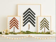 three cross stitch christmas trees on a mantle