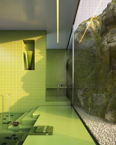 a bathroom with green walls and flooring next to a large rock formation in the background