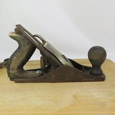 an old metal object sitting on top of a wooden table next to a bottle opener