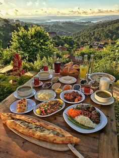 a wooden table topped with lots of plates and bowls filled with different types of food