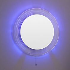 a round mirror is lit up with blue light in the middle and on the wall