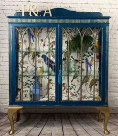 a blue cabinet with glass doors and birds on it