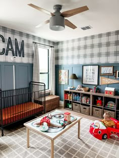 a baby's room with blue walls and plaid wallpaper, a red toy car on the coffee table