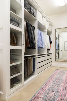 a walk in closet filled with lots of clothes and shoes next to a large rug