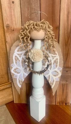 a white candle holder with an angel on it's head and lace over the top