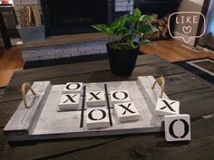 a wooden ticquet game sitting on top of a table next to a potted plant