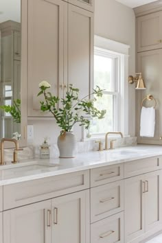 Elegant bathroom vanity with marble countertop, brass fixtures, and a vase of flowers next to a window. Bright And Airy Master Bath, Small Bathroom Remodel Neutral Colors, Master Bath Cabinet Color Ideas, White Cabinet Bathroom Ideas Master Bath, Wood Look Bathroom Floor, Cream Cabinet Bathroom, Creamy Bathroom Cabinets, Tone On Tone Bathroom, Light Colored Bathrooms