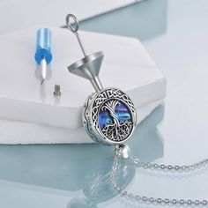 a necklace with a tree of life design on it and a pen next to it