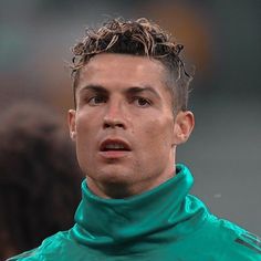 a close up of a soccer player wearing a green jacket and looking off to the side